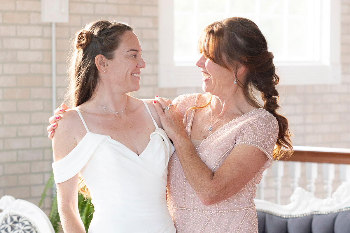 Two mothers dressed elegantly, smiling and standing together, representing love and celebration for special occasions